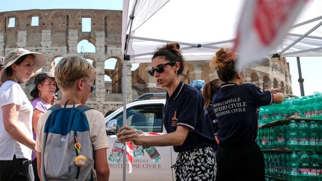 Members of the Italian Civil Protection (Protezione Civile) distribute water bottles to people and tourists in front of the Ancient Colosseum, in central Rome. The national farmers’ union, Coldiretti, said that milk production was down 15% as cows suffered from the heat. At the same time, ice cream consumption was up 30% over the past week, the union said. (Andreas Solaro / AFP) 
