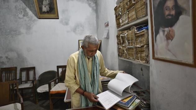 Bhairav Nath Shukla, has been Mukti Bhavan’s manager for the last 40 years. Shukla hosts people when they are close to death, allocating one of the Bhavan’s 10 rooms to them and supervises the transition from material to immortal. He has done this more than 12,000 times. Piles of hard-bound registers recording these details, smelling of seepage, sit stacked besides him. (Sanchit Khanna / HT Photo) Bhairav Nath Shukla, has been Mukti Bhavan’s manager for the last 40 years. Shukla hosts people when they are close to death, allocating one of the Bhavan’s 10 rooms to them and supervises the transition from material to immortal. He has done this more than 12,000 times. Piles of hard-bound registers recording these details, smelling of seepage, sit stacked besides him. (Sanchit Khanna / HT Photo)