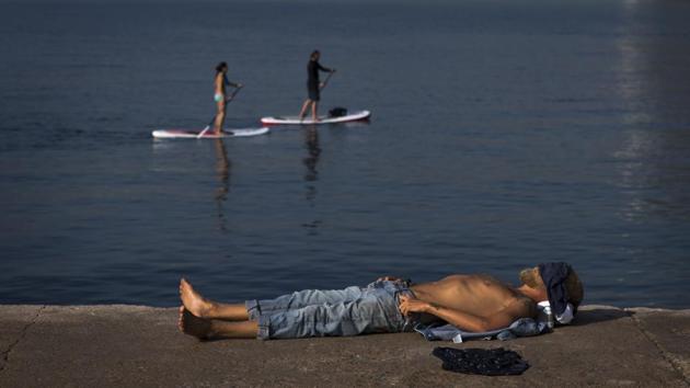 A man rests next to the beach in Barcelona, Spain on Friday. Hot air from Africa is bringing a heat wave to Europe, prompting health warnings about Sahara Desert dust and exceptionally high temperatures. A middle-aged man in Barcelona was found collapsed on a street and taken to hospital where he died of heatstroke. Two other men also died earlier this week. (Emilio Morenatti / AP) 