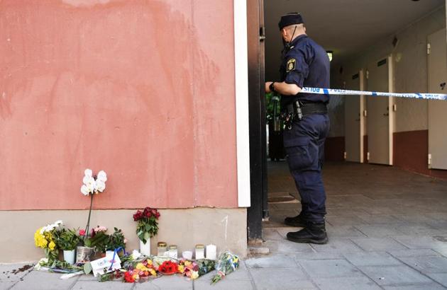 A police officer stands at a cordon, next to flowers and condolences outside the place where a 20 year old man with Down Syndrome, who was carrying a toy gun, was shot and killed by the police in Stockholm, Sweden.(REUTERS)