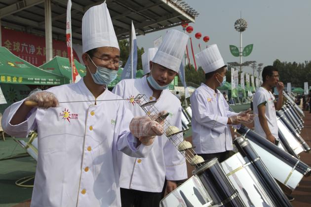 Chefs prepare to cook buns in a solar cooker that using a metal and glass vacuum tube heated by mirrors curved to capture the sun's heat in Dezhou in the eastern Shandong province in China.(AP)
