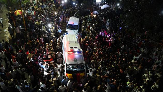 DMK party supporters gather around the ambulence carrying the body of party president M Karunanidhi.(AFP Photo)