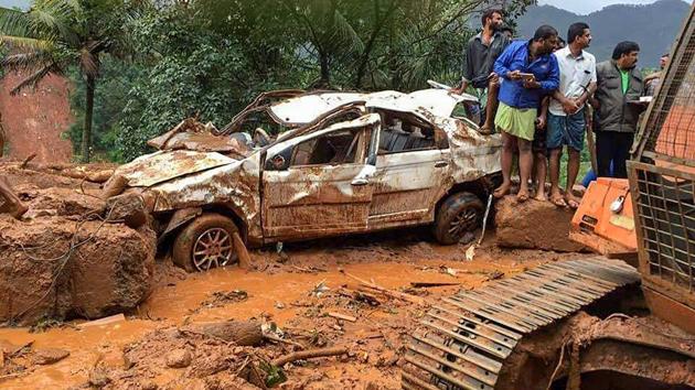 People inspect a damaged car following a landslide, triggered by heavy rains, in Idukki.(PTI Photo)