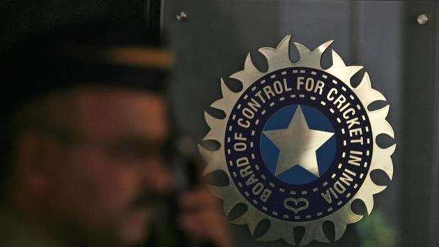 File Photo: A policeman walks past a logo of the Board of Control for Cricket in India (BCCI)
