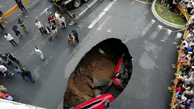 People gather near the scene where two vehicles have fallen into a sinkhole on a street in Harbin, Heilongjiang province, China. (REUTERS) People gather near the scene where two vehicles have fallen into a sinkhole on a street in Harbin, Heilongjiang province, China. (REUTERS)