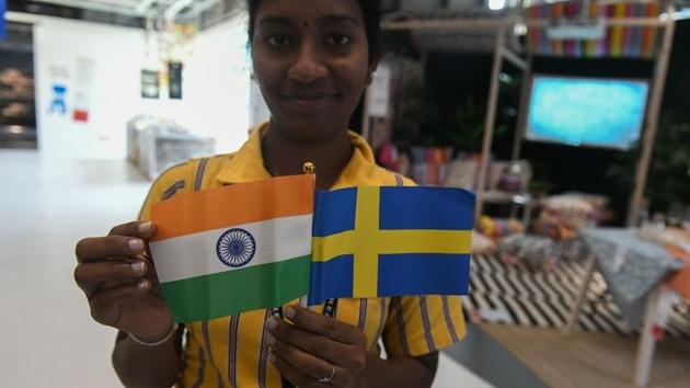 A worker holds flags of India and Sweden during the opening ceremony of the new IKEA store in Hyderabad. (Noah Seelam / AFP)