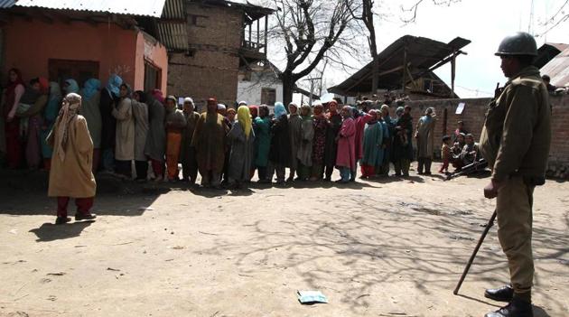 A security personnel stands guard as people line up to vote during the last panchayat polls held in Jammu and Kashmir in 2011. (HT File Photo)