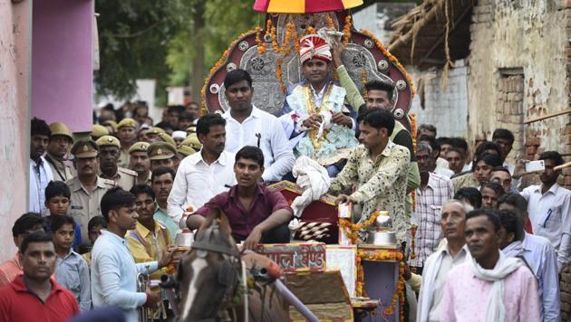 Sanjay Jatav (C), 27, is escorted by the police as he reaches his bride’s village in Nizampur with his wedding procession on July 15, 2018 in Kasganj, Uttar Pradesh. Jatav’s wedding became grander as the day loomed closer, from the number of cars in his baraat (finally fixed at 100) to the number of VIPs in his guest list. He hadn’t always planned on a spectacle however. (Burhaan Kinu / HT Photo) Sanjay Jatav (C), 27, is escorted by the police as he reaches his bride’s village in Nizampur with his wedding procession on July 15, 2018 in Kasganj, Uttar Pradesh. Jatav’s wedding became grander as the day loomed closer, from the number of cars in his baraat (finally fixed at 100) to the number of VIPs in his guest list. He hadn’t always planned on a spectacle however. (Burhaan Kinu / HT Photo)