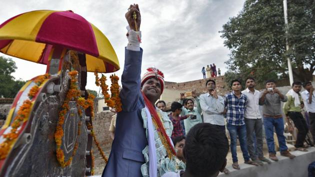 Dressed in a powder-blue suit tailored in Aligarh, Jatav arrived in a pristine white car followed by an armed bodyguard and holding a filigreed dagger in his hands. He grew more and more excited as his vehicle approached Nizampur. One moment he declared that he looked as lavish “as a Thakur”; the next moment he said he felt like a “cabinet minister.” (Burhaan Kinu / HT Photo) Dressed in a powder-blue suit tailored in Aligarh, Jatav arrived in a pristine white car followed by an armed bodyguard and holding a filigreed dagger in his hands. He grew more and more excited as his vehicle approached Nizampur. One moment he declared that he looked as lavish “as a Thakur”; the next moment he said he felt like a “cabinet minister.” (Burhaan Kinu / HT Photo)