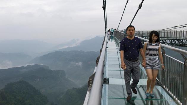 In this photo taken on June 1, 2017, a couple walks on a glass-bottomed skywalk, certified as the world's longest, at the Ordovician park in Wansheng. (AFP) In this photo taken on June 1, 2017, a couple walks on a glass-bottomed skywalk, certified as the world's longest, at the Ordovician park in Wansheng. (AFP)