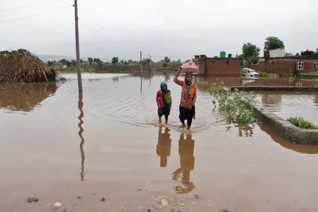 Residents wade through a submerged area following a flash flood triggered by heavy rains in Jammu. The Amarnath Yatra has also been suspended. (PTI)