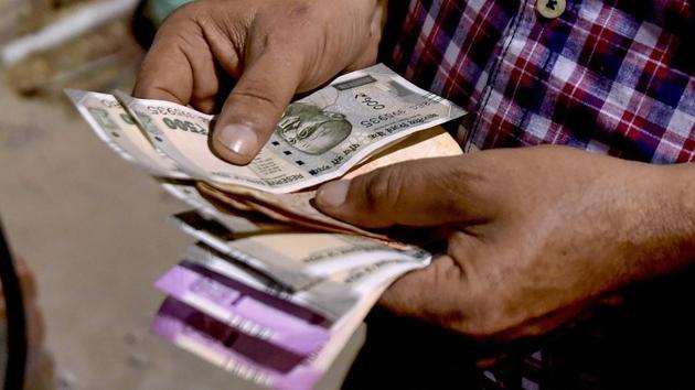 A customer counts rupee notes at a fuel station, in Kolkata. (PTI File Photo) A customer counts rupee notes at a fuel station, in Kolkata. (PTI File Photo)
