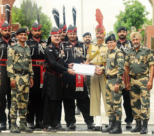 Pakistani Wing Commander Bilal (4L) presents sweets to Indian Border Security Force (BSF) Commandant Sudeep (2R) during a ceremony to celebrate Pakistan's Independence Day at the India-Pakistan Wagah border post at Attari on Tuesday. (Sameer Sehgal/HT)