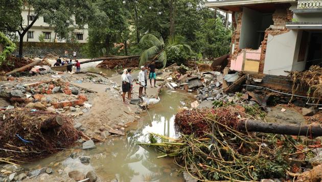 People walk by houses destroyed by flood waters at Kannappankundu in Kozhikode, in Kerala on August 10, 2018.(AFP)