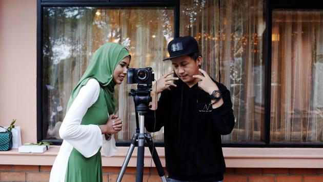 Win Lae Phyu Sin talks to a videographer after attending a beauty product launch event. She remains undeterred by those who denigrate her for being a Muslim and wearing a hijab that exposes the face. “’Don’t you know you will go to hell if you do that? Why don’t you take off the hijab during shooting?’” she quoted some Facebook critics as asking. (Ann Wang / REUTERS) 