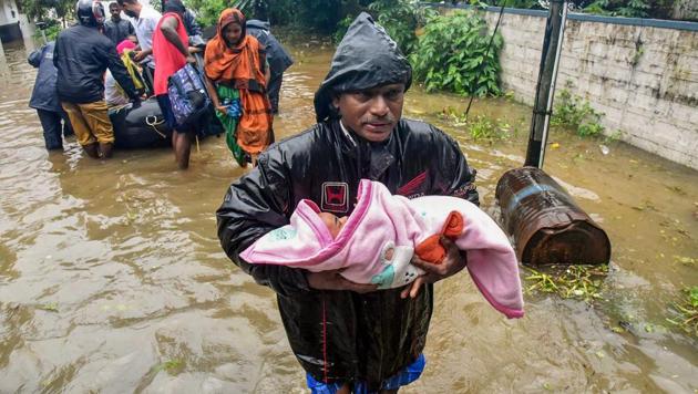 A rescuer carries an infant as people are evacuated from a flood-hit locality in Kochi on August 15, 2018.(PTI)