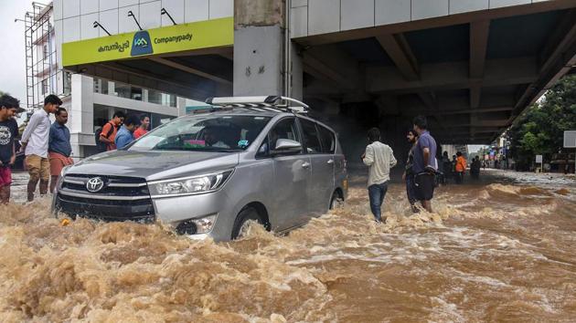 People wade across a waterlogged street at a flood-affected region following heavy monsoon rainfall, in Kochi.(PTI Photo)