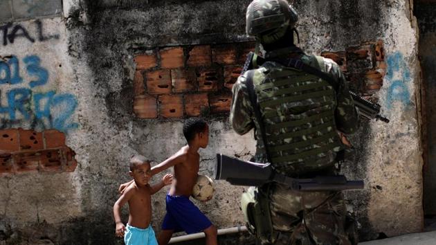 Kids observe as Brazilian armed forces member patrolling during an operation against drug gangs in Lins slums complex in Rio de Janeiro, Brazil. (Ricardo Moraes / REUTERS) Kids observe as Brazilian armed forces member patrolling during an operation against drug gangs in Lins slums complex in Rio de Janeiro, Brazil. (Ricardo Moraes / REUTERS)