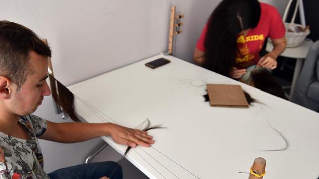 Volunteers weave hair to create wigs specifically for children who are undergoing chemotherapy or have lost their hair due to other health complications. “As trivial as it might seem at first while a person is battling such an aggressive disease, hair loss is often a huge psychological burden, particularly for girls who do not dare to go out without hair,” said Nizic. (Elvis Barukcic / AFP) 