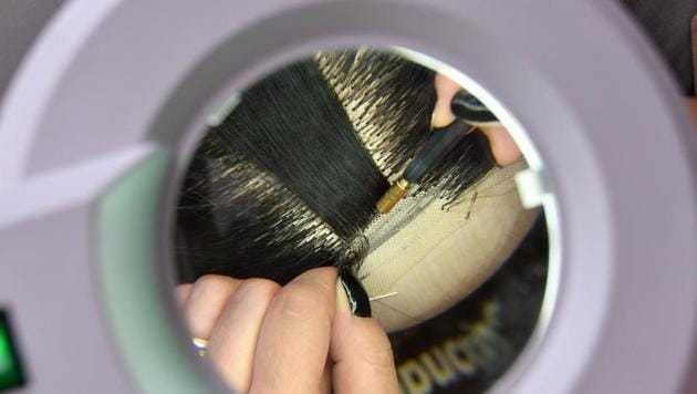 It takes at least two weeks -- and the hair of six people -- to weave one wig. The small studio is also training a dozen future weavers to carry on the exacting work, which involves using a small metal needle to sew strands of hair into a mesh cap that covers the head. (Elvis Barukcic / AFP) 