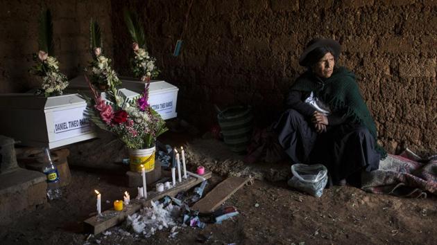 Marta Tineo Espinosa sits next to the coffins of her relatives in Tantana, Peru. Under this new measure, authorities can turn over remains uncovered by forensic scientists before determining a cause of death or completing an investigation. Families are also no longer required to file a complaint with the chief prosecutor’s office first. (Rodrigo Abd / AP)