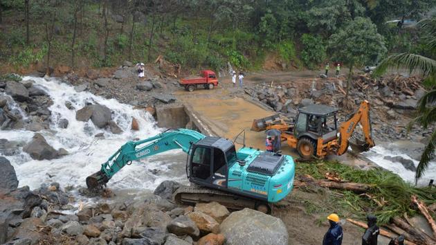 People look at a loader machine removing boulders and blockage moved by a landslide at Mattikunnu village in Kozhikode district, Kerala. (Manjunath Kiran/AFP Photo)