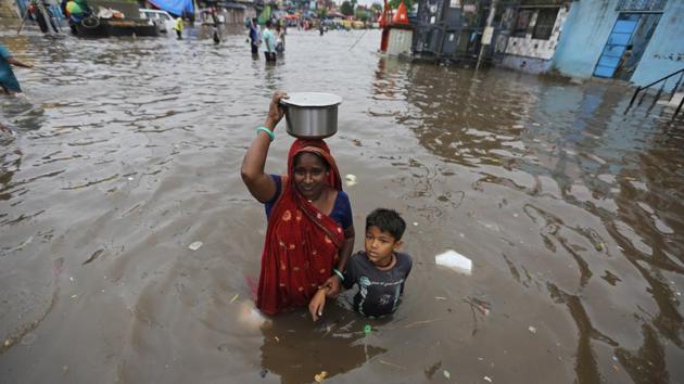 A woman and a child wade past floodwaters after heavy rainfall in Ahmadabad, Gujarat. (Ajit Solanki / AP) 