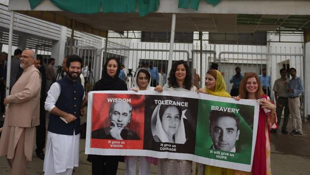 Supporters of Pakistan Peoples party hold a placard with the pictures of (L-R) late former Pakistani premier Zulfikar Ali Bhutto and his daughter late former premier Benazir Bhutto and grandson Bilawal Bhutto during the first session of the parliament after the general election, in Islamabad on August 13, 2018.(AFP Photo)