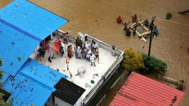 People wait for aid on the roof of their house at a flooded area in Kerala, August 17, 2018.(Reuters)