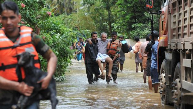 Rescue personnel carry animals and elderly people to safety during a rescue operation in Thrissur’s Mala village on Sunday.(AFP Photo)