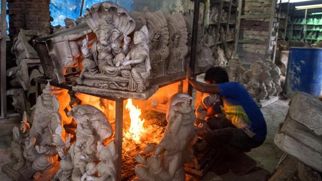 A worker lights up a fire around Ganesha idols to speed up the drying process during damp monsoon days. Hazare says that he’s been following the same natural crafting process and has passed down the knowledge over the years. With his great-grandson now helping out, he hopes the practice moves down another generation. (Satish Bate / HT Photo) A worker lights up a fire around Ganesha idols to speed up the drying process during damp monsoon days. Hazare says that he’s been following the same natural crafting process and has passed down the knowledge over the years. With his great-grandson now helping out, he hopes the practice moves down another generation. (Satish Bate / HT Photo)
