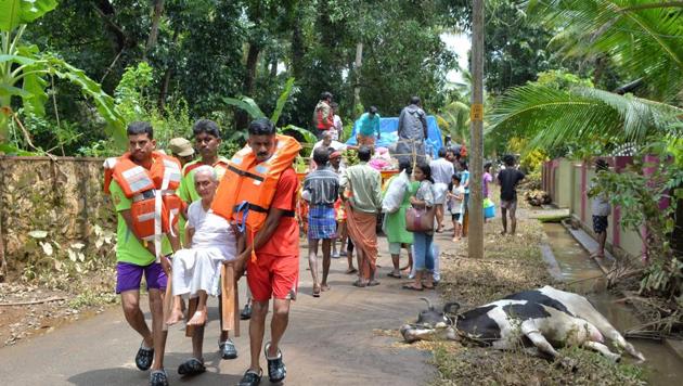 The carcass of a cow lies on the side of a road while an eldery woman is carried to safety from flood waters during a rescue operation by Kerala and Tamil Nadu Fire Force personnel in Annamanada village in Thrissur District, Kerala, on August 19, 2018. (AFP) The carcass of a cow lies on the side of a road while an eldery woman is carried to safety from flood waters during a rescue operation by Kerala and Tamil Nadu Fire Force personnel in Annamanada village in Thrissur District, Kerala, on August 19, 2018. (AFP)