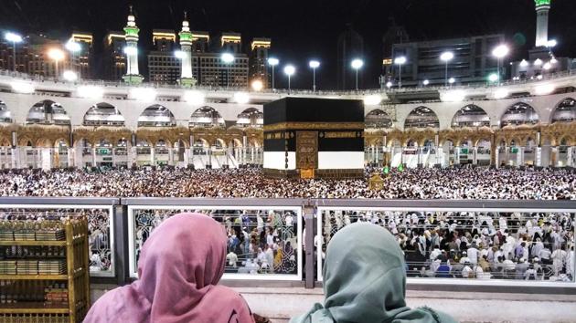 Muslim worshippers watch as others circumambulate around the Kaaba. Wearing the simple white garb of the pilgrim, most of the faithful began moving on Sunday from Mecca to the nearby Mina valley. (Ahmad Al-Rubaye / AFP)