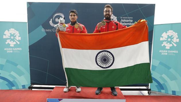 Bonze medalist India's Abhishek Verma, right, and gold medalist India's Saurabh Chaudhary, poses for photographer with India national flag after the 10m air pistol men's final shooting event during the 18th Asian Games in Palembang, Indonesia, Tuesday, Aug. 21, 2018.(AP)