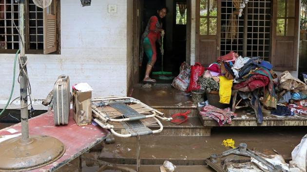 A woman cleans the mud from the entrance of her house following floods in Paravur in the southern state of Kerala on August 21, 2018.(Reuters Photo)