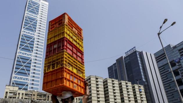 A worker carries a stack of crates on his head in front of the Sunshine Tower, developed by Sunshine Housing & Infrastructure Pvt., left, in the Dadar area of Mumbai. (Dhiraj Singh/Bloomberg) A worker carries a stack of crates on his head in front of the Sunshine Tower, developed by Sunshine Housing & Infrastructure Pvt., left, in the Dadar area of Mumbai. (Dhiraj Singh/Bloomberg)
