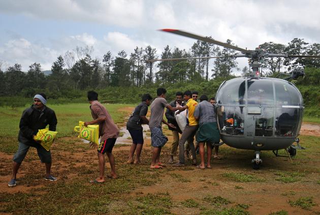 Flood victims unload food and relief material from an Indian Air force helicopter at Nelliyampathy Village, Kerala, August 21, 2018.(REUTERS)