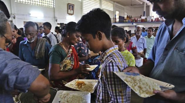 Flood-affected people receive food at a relief camp set up inside a school in Kochi in Kerala on August 23, 2018.(AP)