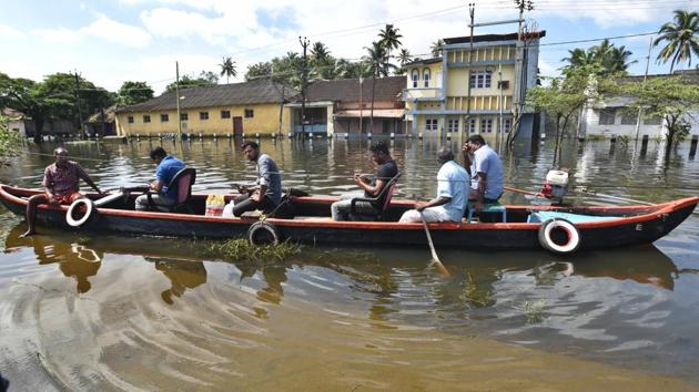 Fisherman help flood victims to reach their marooned houses in the outskirts of Alappuzha district of Kerala.(Raj K Raj/HT Photo)