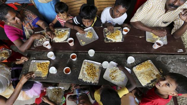 A group of flood affected people, mostly children, sit together to have a meal at a relief camp set up inside a school in Kochi.(AP Photo)