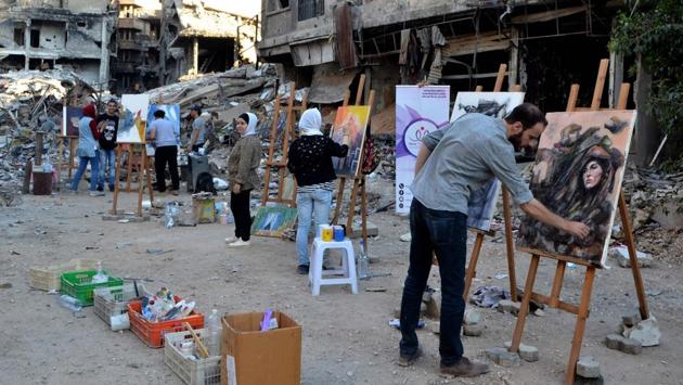Artists paint in the Yarmuk refugee camp on the southern outskirts of Damascus. Before the war, Yarmuk was home to around 160,000, the United Nations says. Set up in 1957 to house Palestinian refugees, over the decades it became a crowded district that was eventually swallowed up by Damascus. Today, it lies almost deserted. (Maher Al Mounes / AFP)