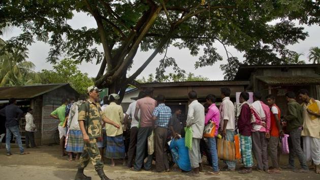 An Indian paramilitary person walks past as people whose names were left out in the National Register of Citizens (NRC) draft stand in a queue to collect forms to file appeals near a NRC center on the outskirts of Guwahati.(AP File Photo) An Indian paramilitary person walks past as people whose names were left out in the National Register of Citizens (NRC) draft stand in a queue to collect forms to file appeals near a NRC center on the outskirts of Guwahati.(AP File Photo)