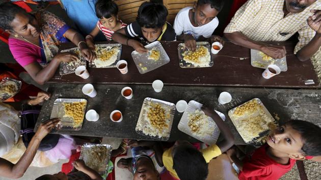 A group of flood affected people mostly children, sit together to have a meal at a relief camp set up inside a school in Kochi, in Kerala, on August 23.(AP Photo)