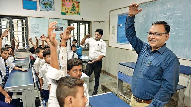 Principal CS Verma (blue shirt) and teacher Suresh Kumar during a happiness class at Kautilya Government Sarvodaya Bal Vidyalaya.(Sanchit Khanna/HT PHOTO)