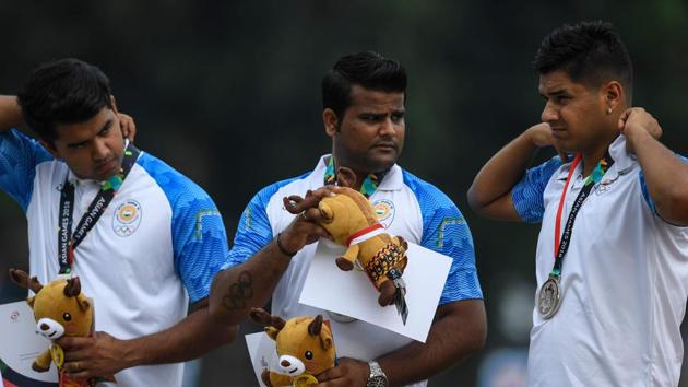 India's Rajat Chauhan, Abhishek Verma and Aman Saini stand on the podium with their medals.(AFP)