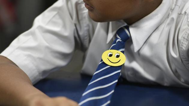 A student listens during the day’s happiness class with a yellow smiley badge pinned to his tie. Kumar, who otherwise teaches English, said it was hard to get the children interested in the happiness class initially, but now they actively participate in lessons. But many students say their parents are sceptical about what they are learning in the happiness classes. (Sanchit Khanna / HT Photo) A student listens during the day’s happiness class with a yellow smiley badge pinned to his tie. Kumar, who otherwise teaches English, said it was hard to get the children interested in the happiness class initially, but now they actively participate in lessons. But many students say their parents are sceptical about what they are learning in the happiness classes. (Sanchit Khanna / HT Photo)
