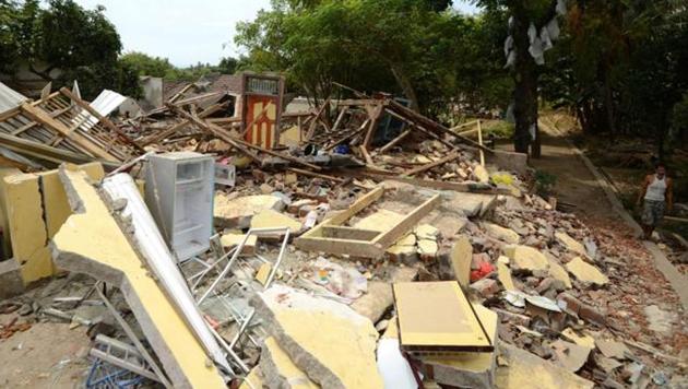 A man (R) walks past collapsed houses in Kayangan in northern Lombok island, following the August 5 earthquake.(AFP Photo)