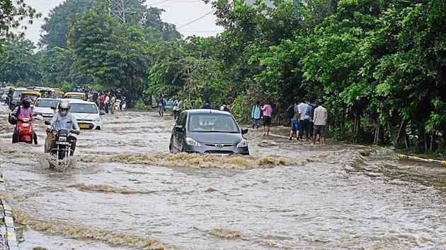 Commuters wade through a waterlogged street in Sector 44, on Tuesday.(Sanjeev Verma/HT PHOTO)