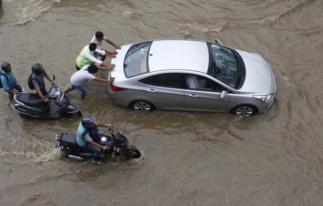 Vehicles get stuck in waterlogged road after heavy rainfall on National Highway 48 near Signature Tower Chowk in Gurugram on Tuesday.(Yogendra Kumar/HT PHOTO)