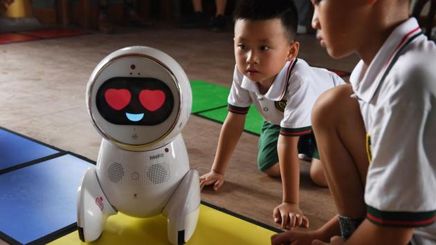 Children watch a Keeko robot make its way on a path they made from square mats at the Yiswind Institute of Multicultural Education in Beijing. (Greg Baker / AFP)